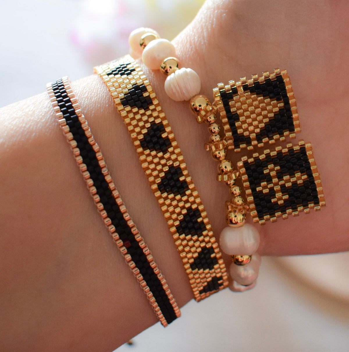 Close-up of a hand wearing multiple beaded bracelets with geometric patterns.