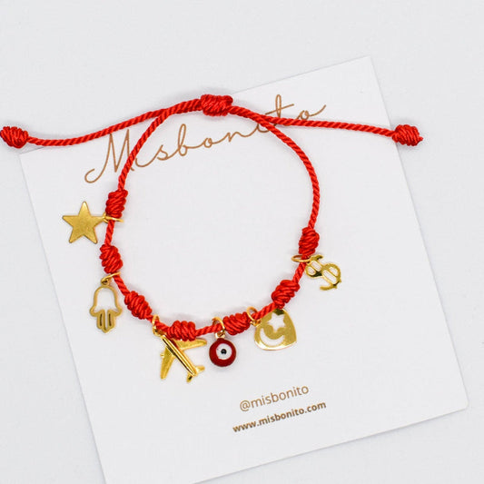 Red braided bracelet with gold charms on a Misbaha branded card.
