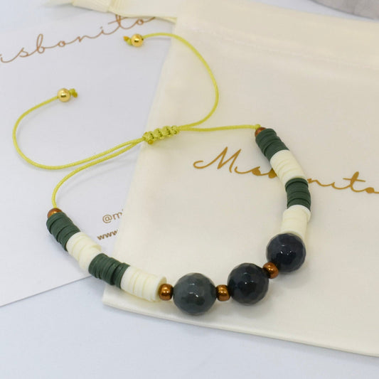 Beaded bracelet with green and white beads on a branded pouch