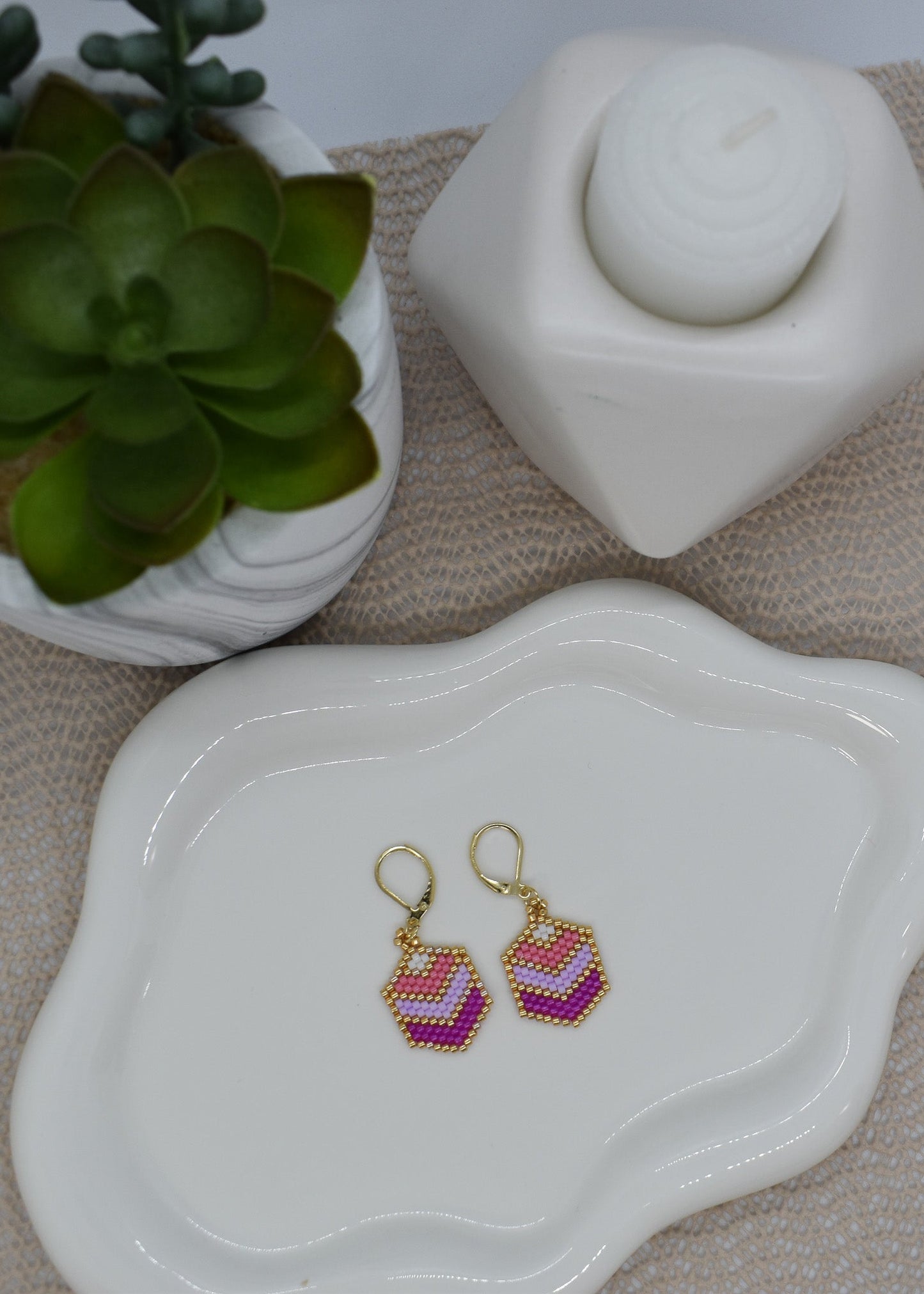 Beaded earrings on a white dish with a plant and decorative item in the background