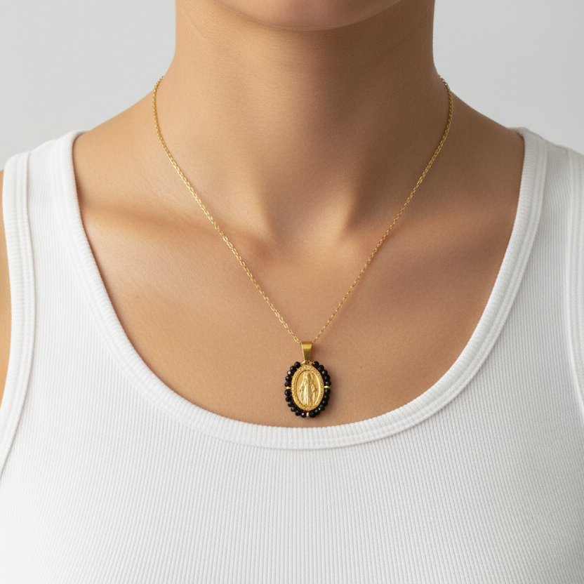 Gold necklace with a black pendant on a white tank top
