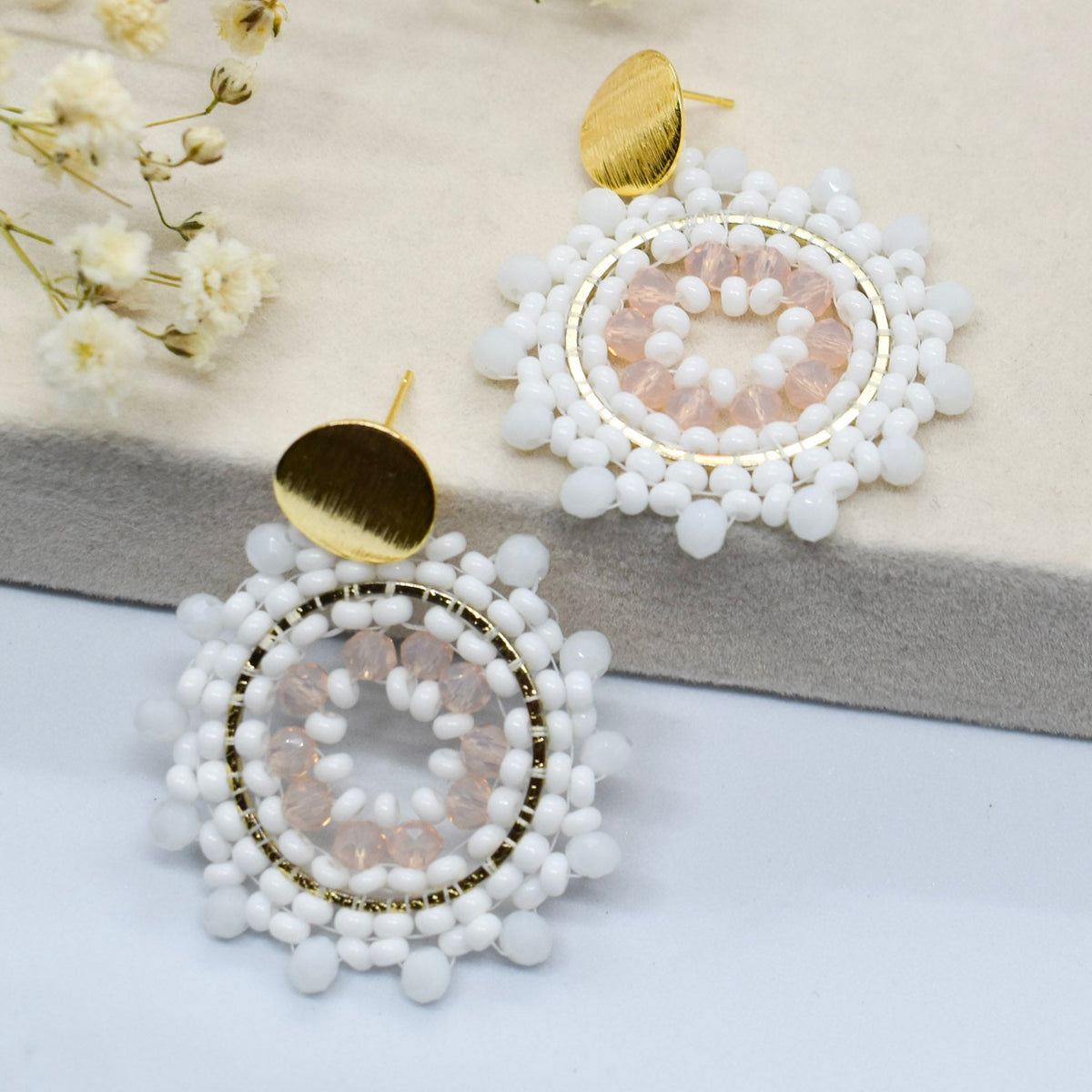 White beaded earrings with gold accents on a light background