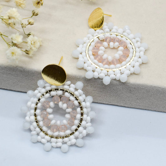White beaded earrings with gold accents on a light background