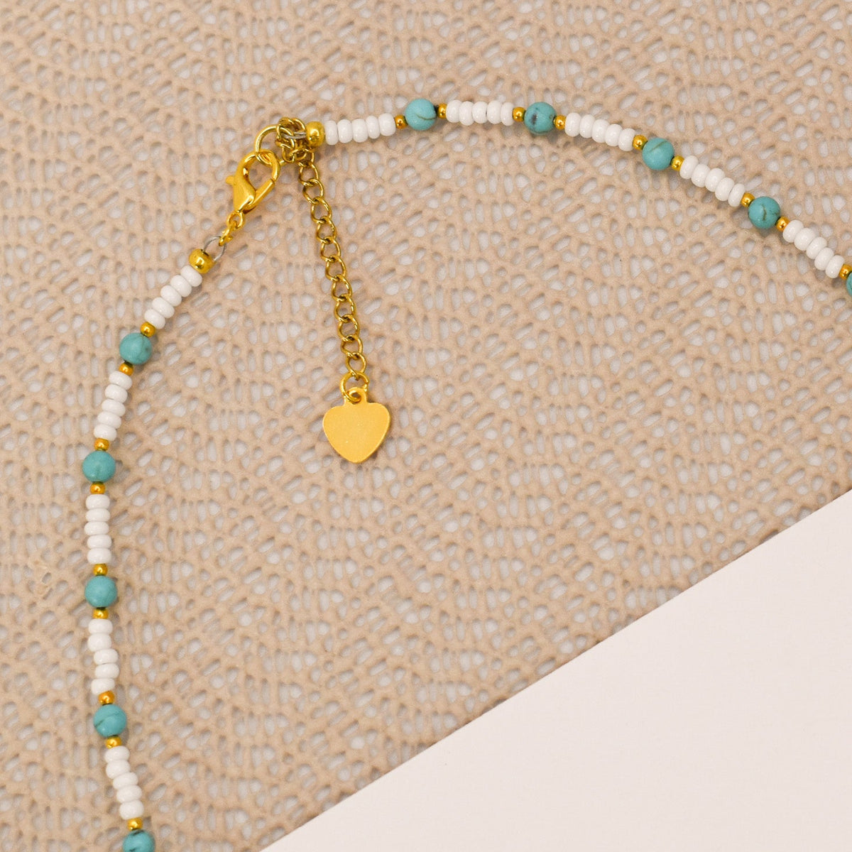 Beaded necklace with heart charm on a textured surface