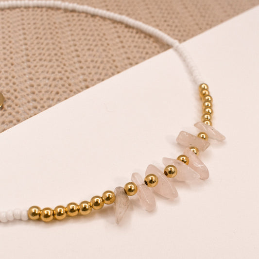 Necklace with gold beads and rose quartz stones on a beige background