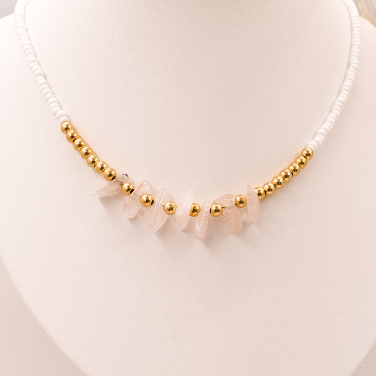 Necklace with gold beads and pink stones on a white background