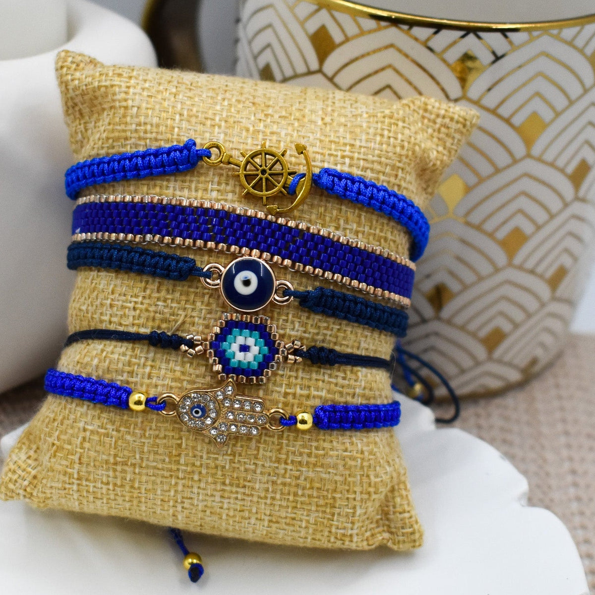 Hand holding a small beaded bracelet with a geometric design on a plain background
