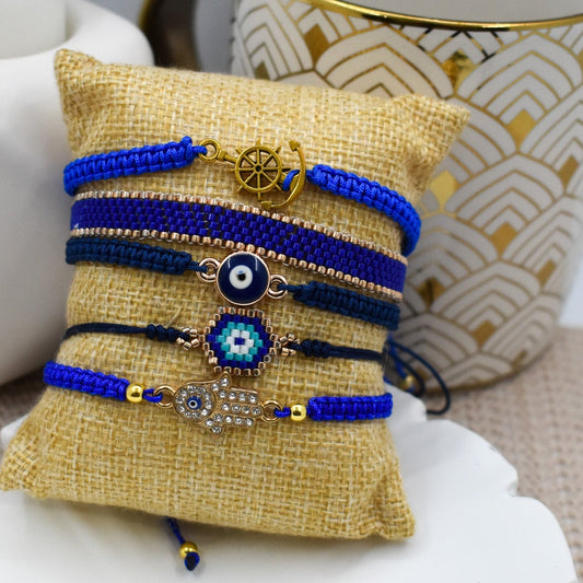 Hand holding a small beaded bracelet with a geometric design on a plain background