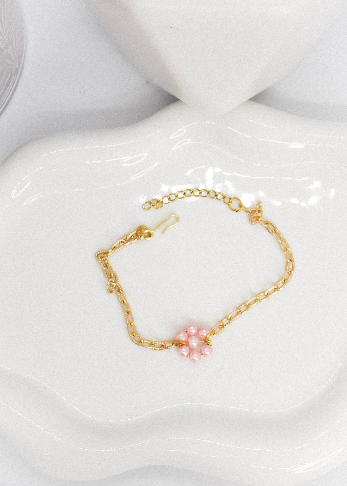 Gold bracelet with daisy flower made with pink pearl on a tray