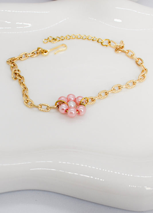 Gold bracelet with pink daisy flower made with pink faux tiny pearls on a tray