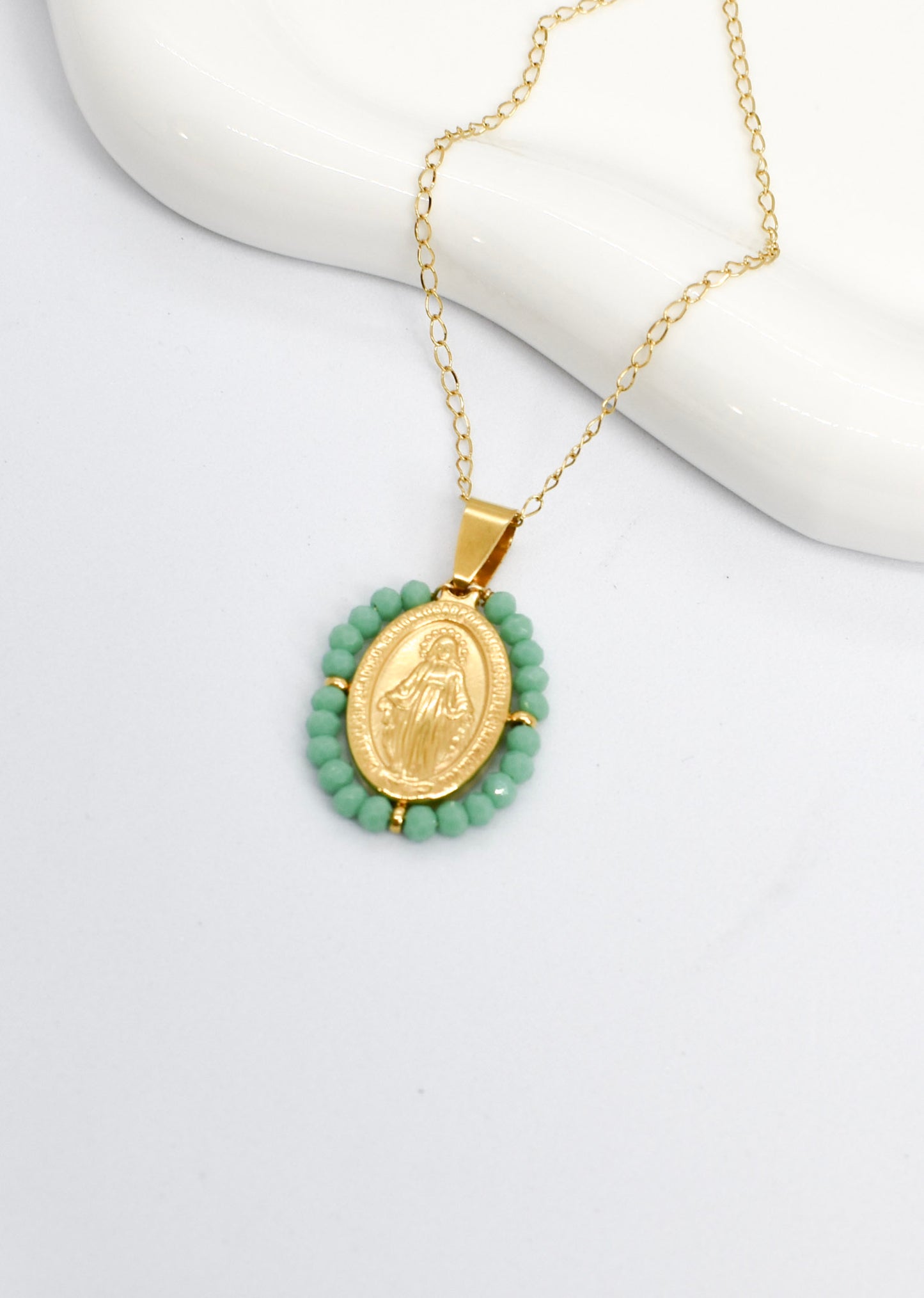 Gold necklace with a green pendant on a white background