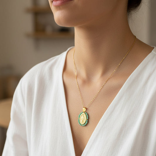 Gold necklace with a green pendant on a white background