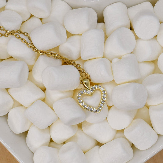 Heart-shaped dish filled with marshmallows and a gold necklace on a wooden surface
