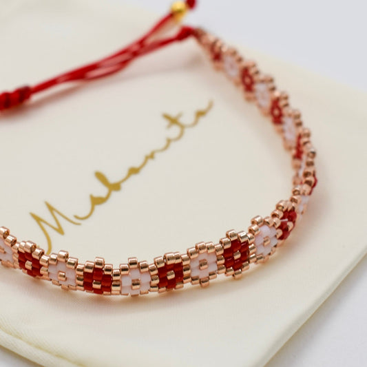 Bracelet with red and gold beads on a white card with 'Maturity' text