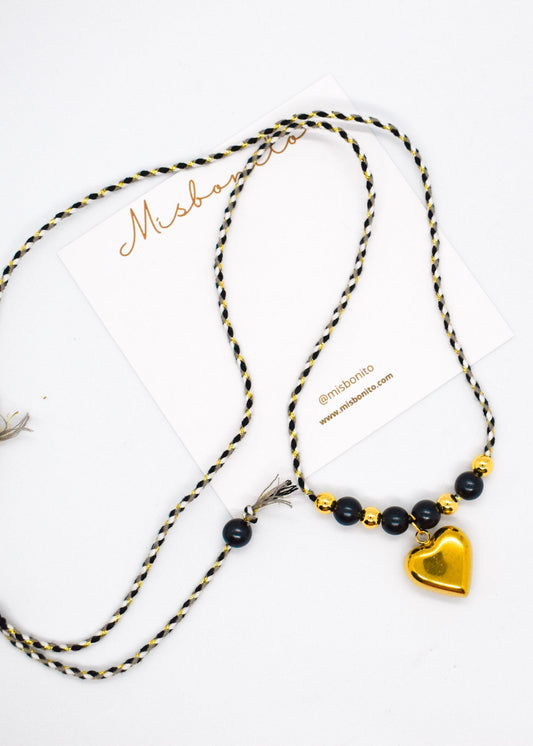 Necklace with black beads and a gold heart pendant on a white background