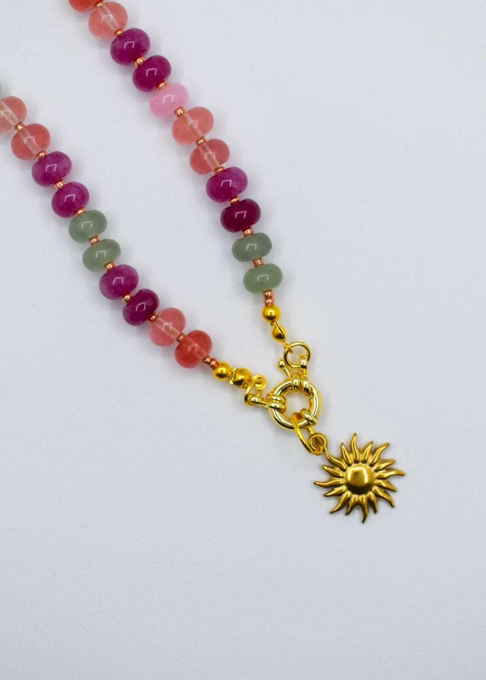 Necklace with multicolored beads and a gold sun pendant on a white background