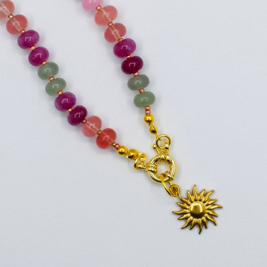 Necklace with multicolored beads and a gold sun pendant on a white background