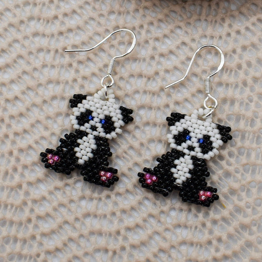 Panda-shaped beaded earrings on a textured surface