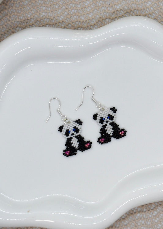 Panda-shaped beaded earrings on a white dish