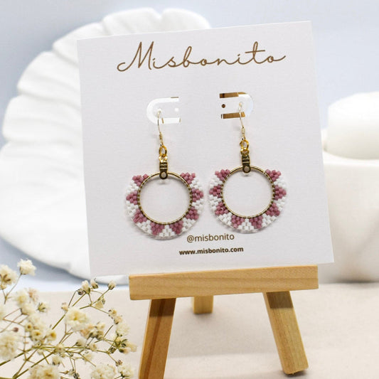 Earrings on a Misbonito branded card with a small wooden stand on a light background.