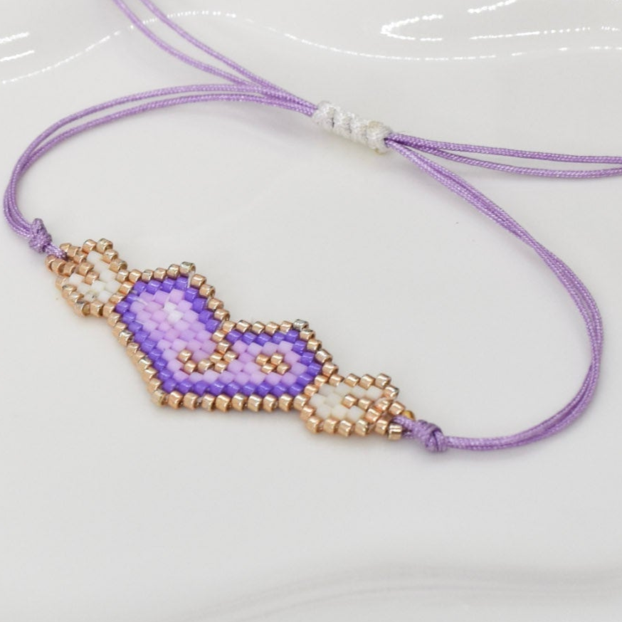 Purple beaded necklace with a heart-shaped pendant on a white surface