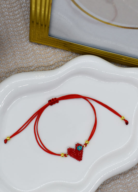 Red bracelet with a heart charm on a white dish