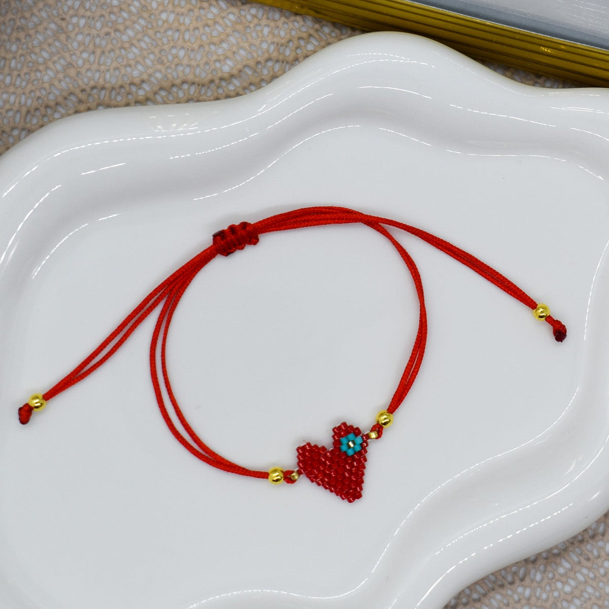 Red bracelet with a heart charm on a white dish