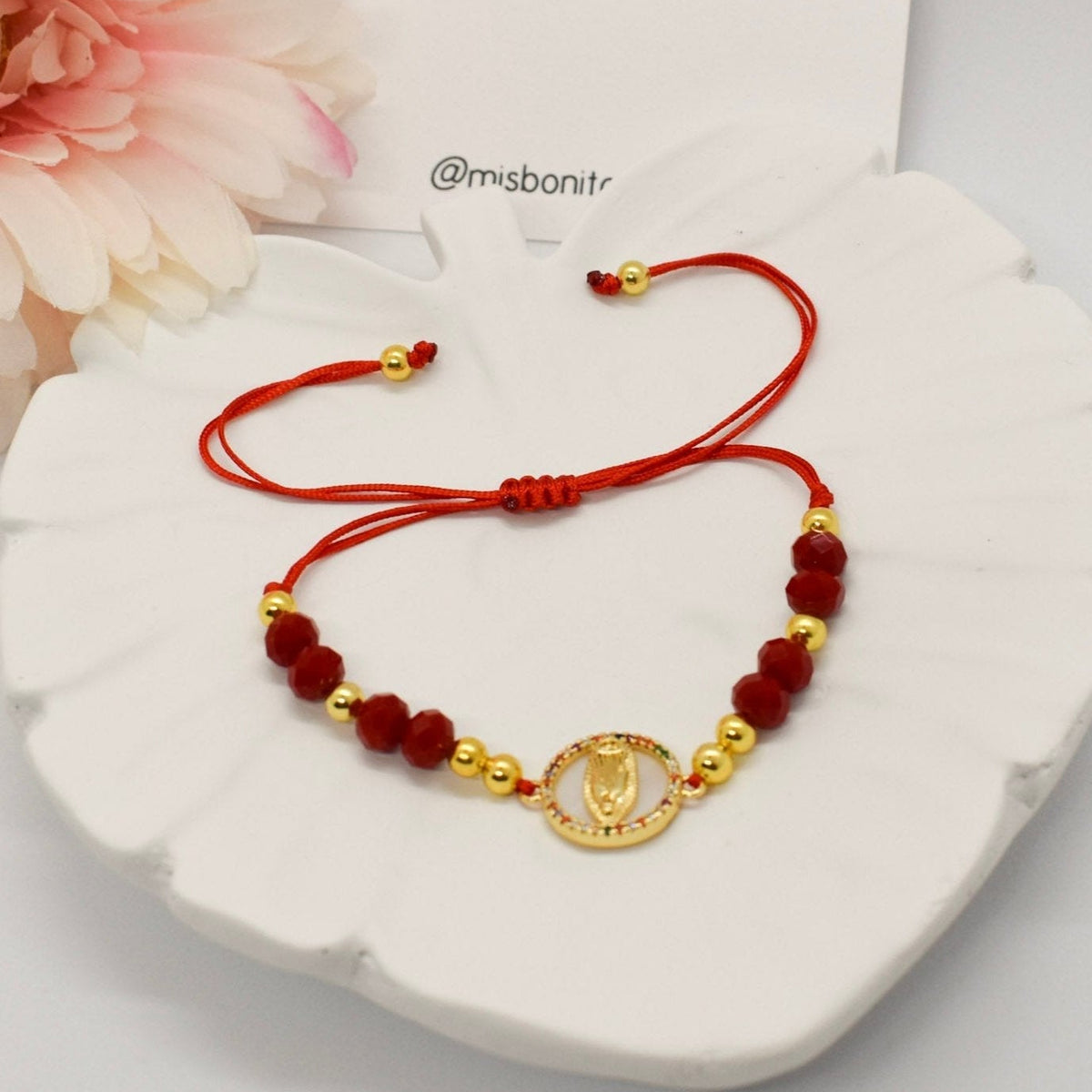Virgin and crystals Bracelet on a leaf tray with a misbonito card and flowers on a corner