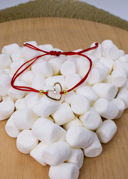 White marshmallows with a red string and gold heart charm on a wooden surface