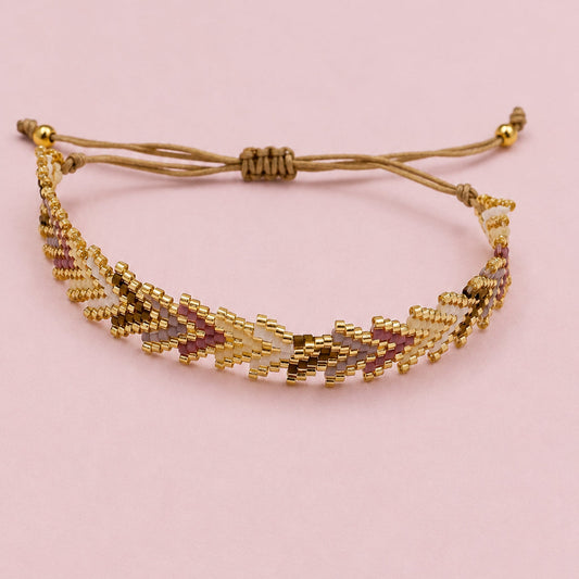 A gold beaded adjustable cord bracelet with a geometric chevron pattern, displayed on a plain white surface.