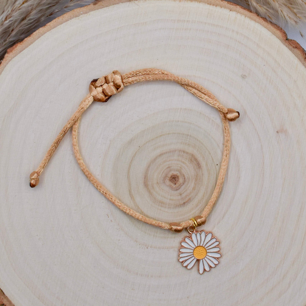 beige and daisy floral bracelet on a wood surface