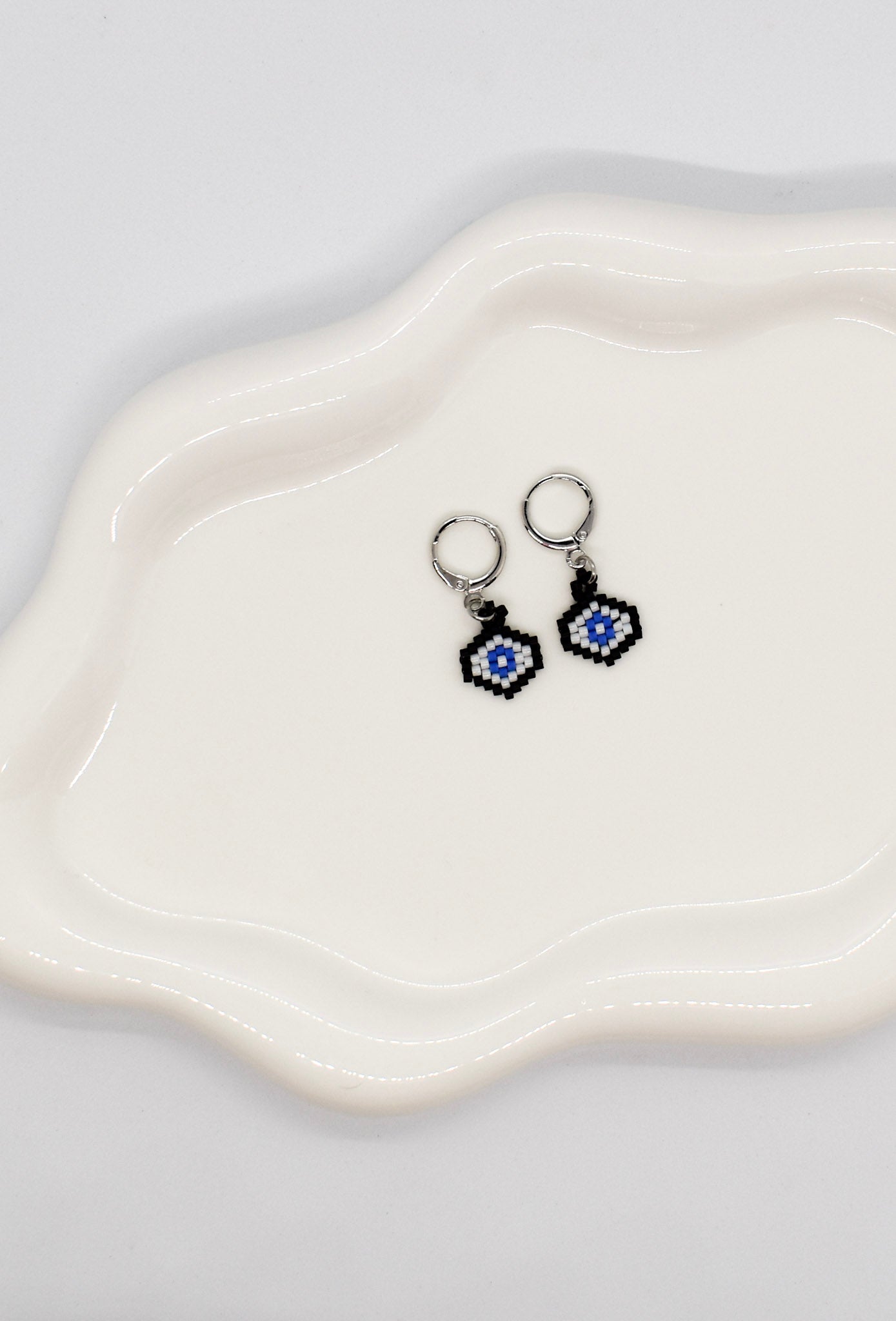 Pair of earrings with blue and black designs on a white dish