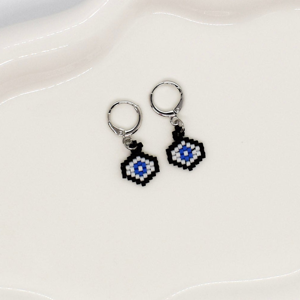 Pair of earrings with blue and black designs on a white dish