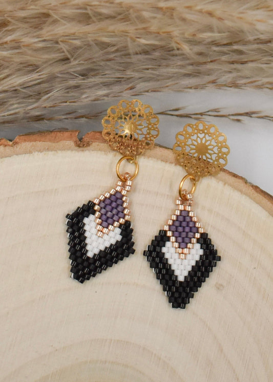 black and white diamond shaped earrings on a wood background