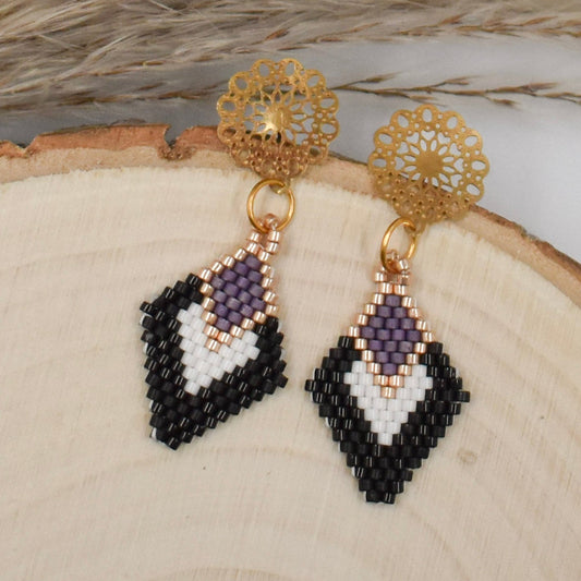 black and white diamond shaped earrings on a wood background
