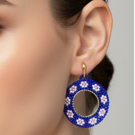 Close-up of a person wearing a blue floral earring with a gray background