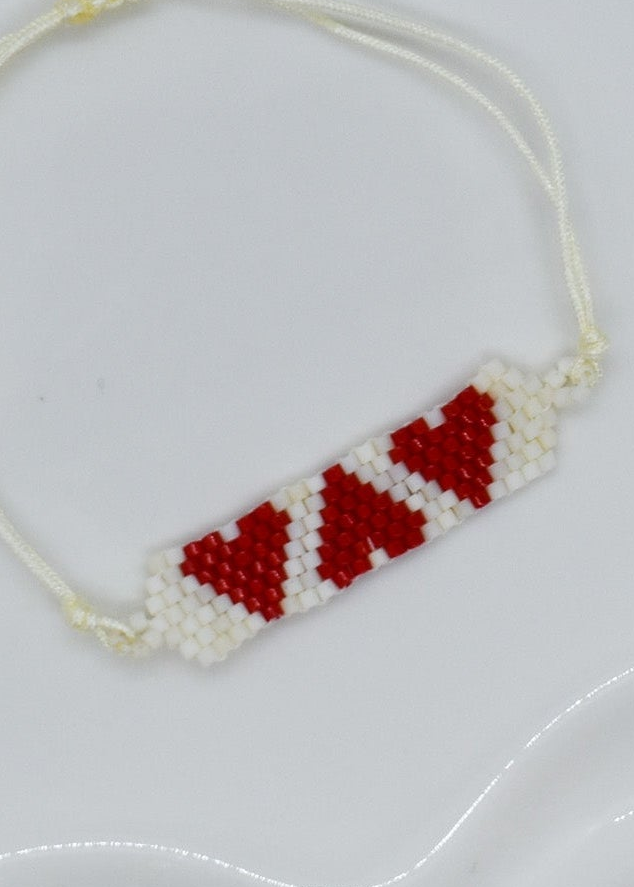Beaded necklace with red and white pattern on a light gray background