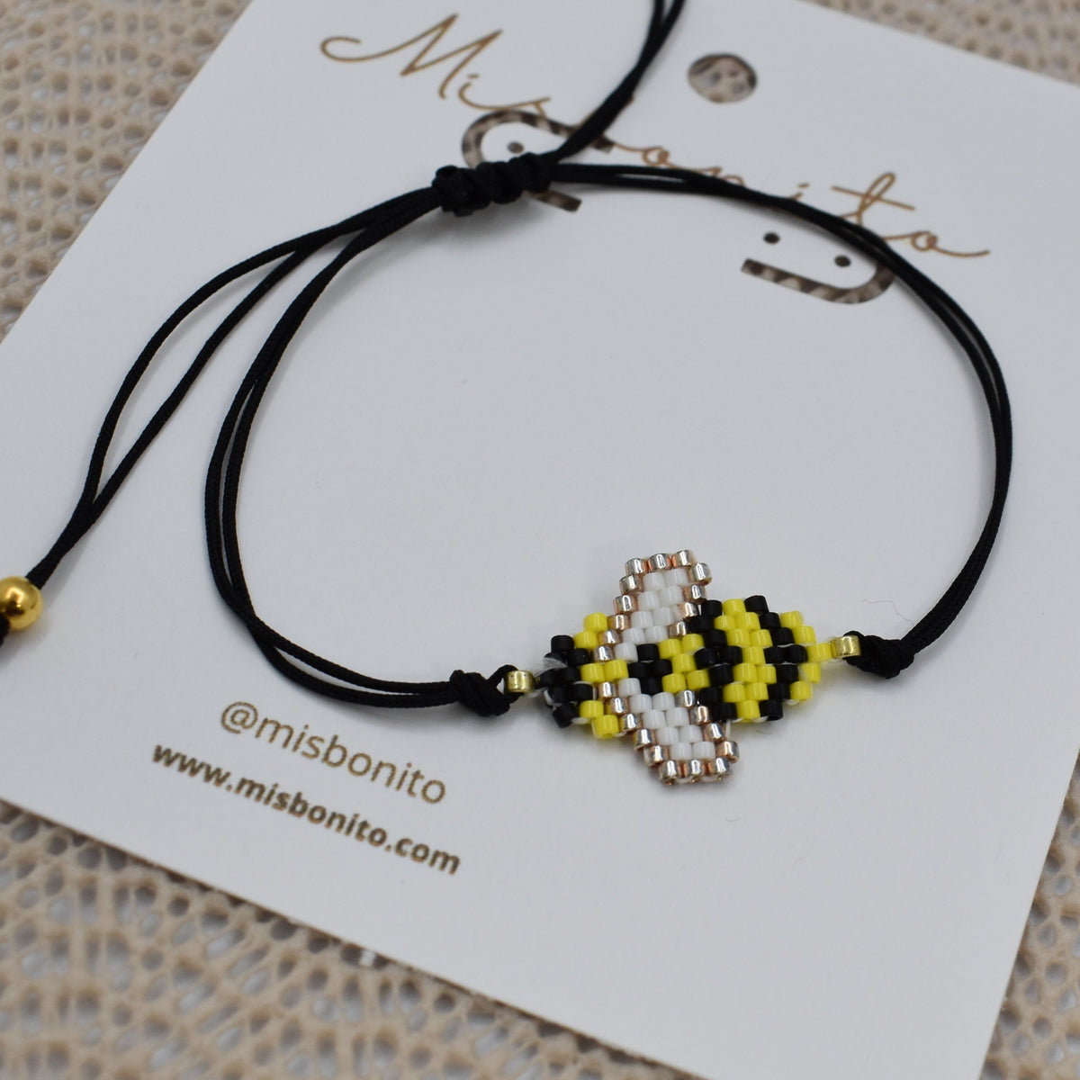 Black bracelet with bee-shaped charms on a branded card