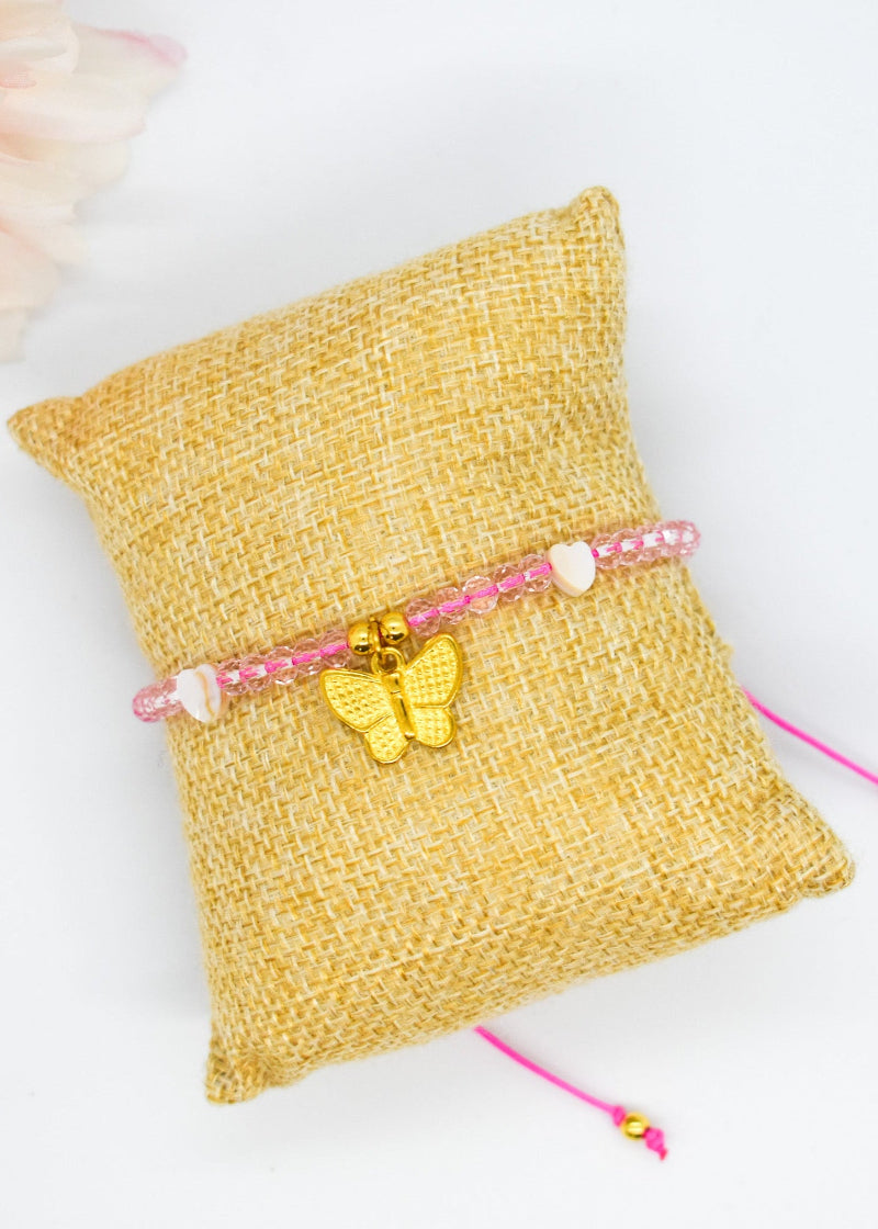 Bracelet with a butterfly charm on a textured yellow pillow with a white background