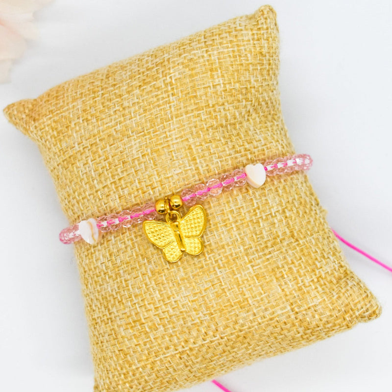 Bracelet with a butterfly charm on a textured yellow pillow with a white background