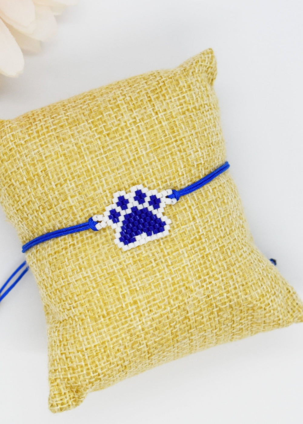 Blue beaded paw bracelet on a pillow
