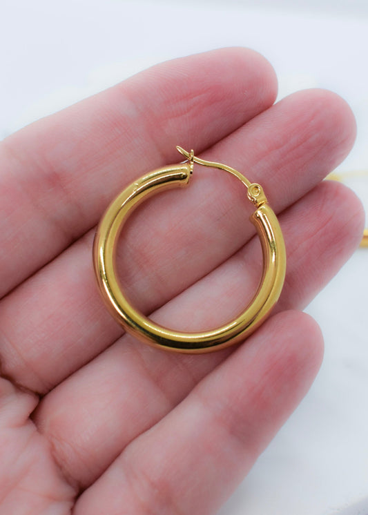 a hand holding golden hoops