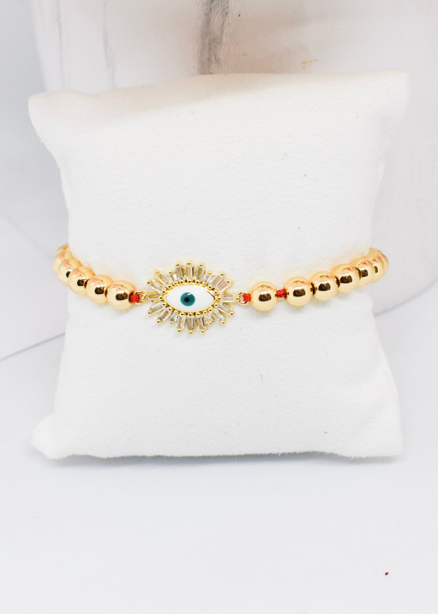 Gold bracelet with a central eye design on a white cushion
