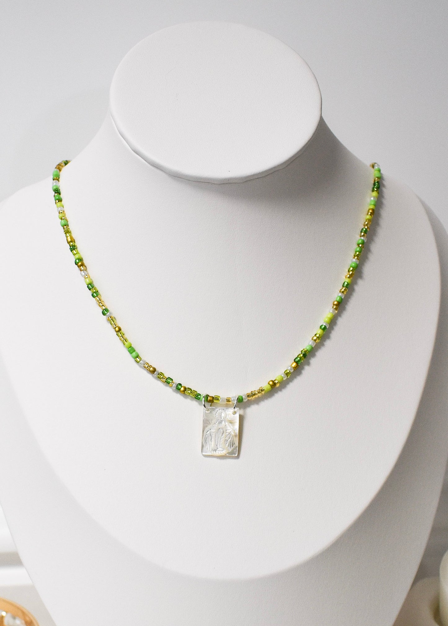 green beaded necklce with white scapula