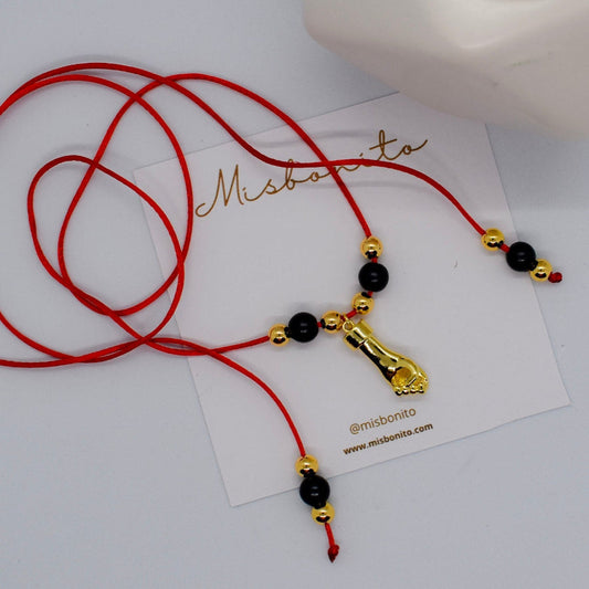 Red cord necklace with black and gold beads on a white card with 'Misbonito' branding.