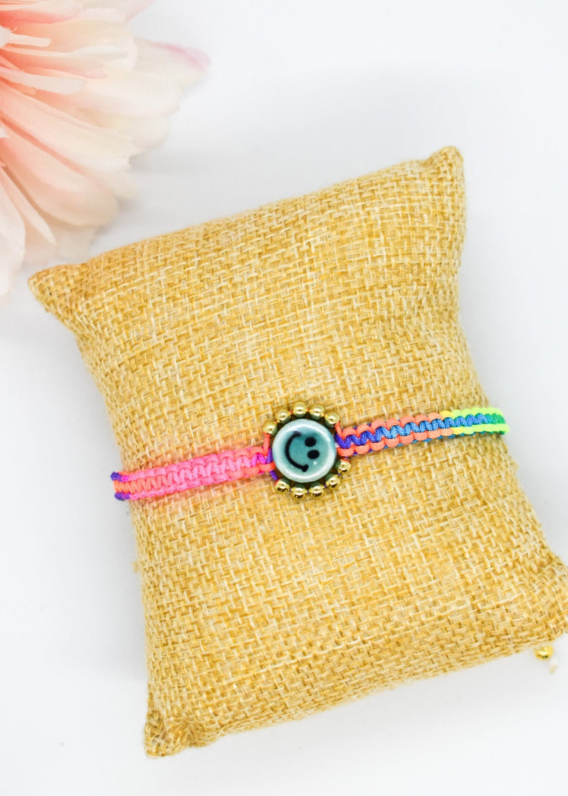 Colorful bracelet on a yellow pillow with a pink flower in the background