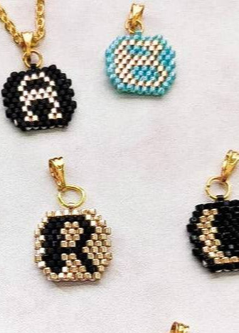 Set of small beaded pendants with letter 'R' on a white background