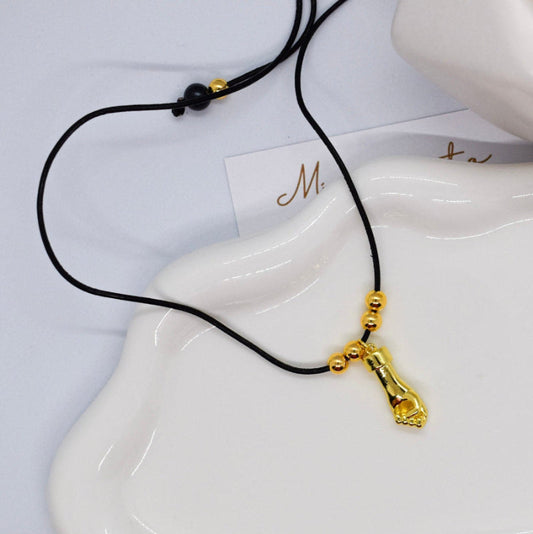 Gold pendant hand necklace on a white dish with a blurred background