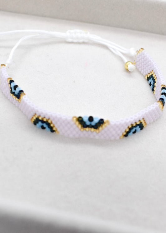 Pink bracelet with blue and gold evil eye pattern on a white background