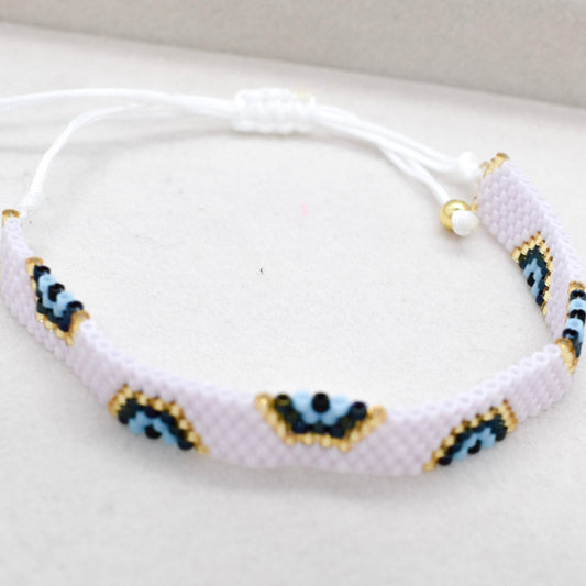 Pink bracelet with blue and gold evil eye pattern on a white background